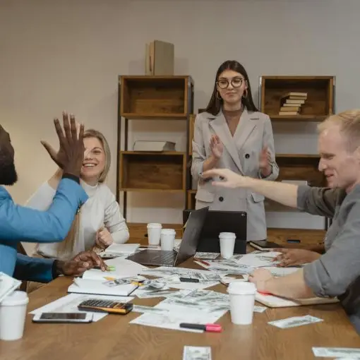 A multicultural team enjoying success during a collaborative business meeting in a modern office.
